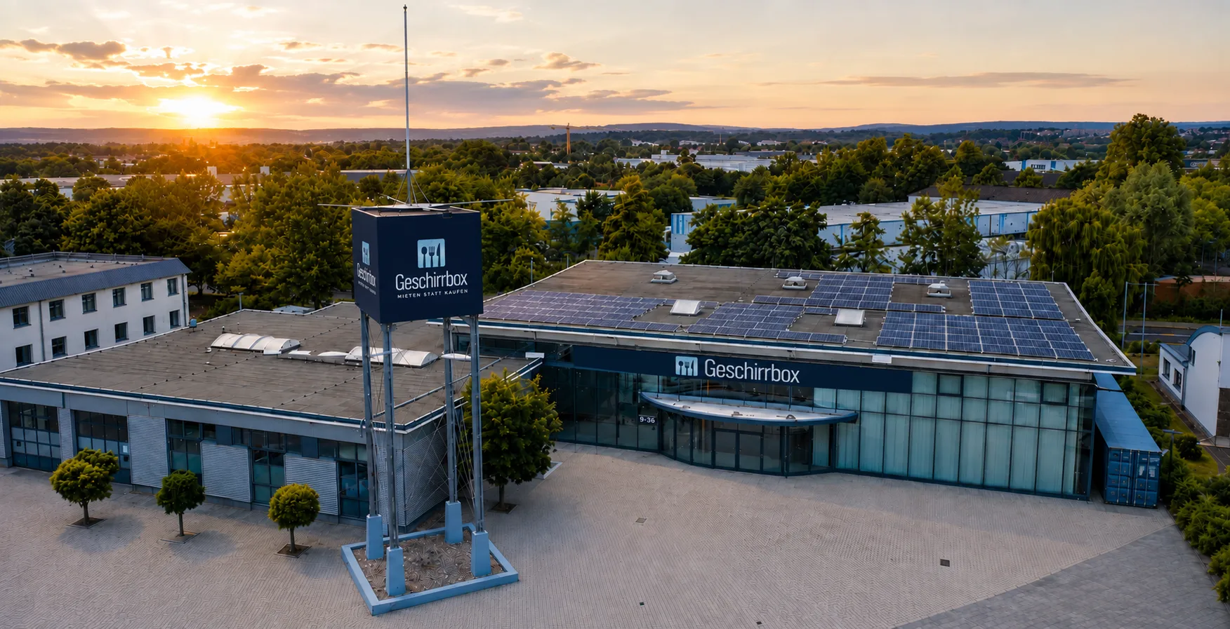 Drohnenaufnahme der Geschirrbox-Halle in Lohfelden bei Sonnenuntergang, mit Photovoltaikanlage auf dem Dach